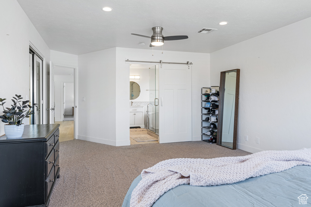 Bedroom featuring a barn door, carpet, connected bathroom, and ceiling fan