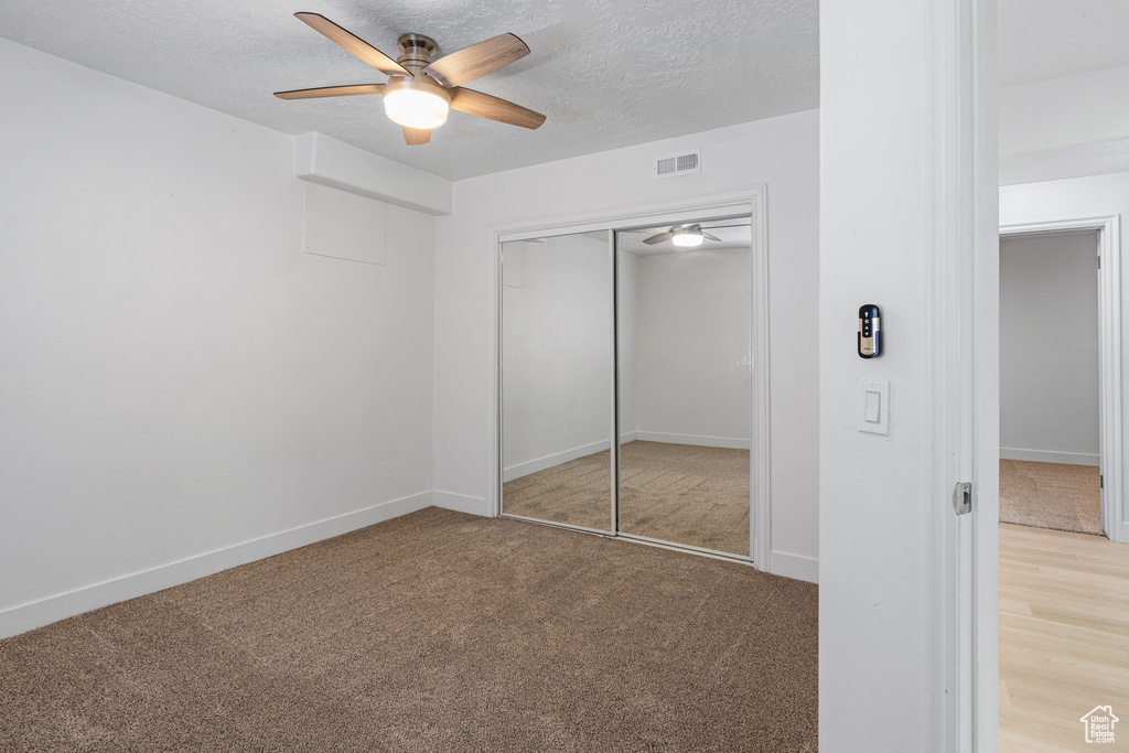 Unfurnished bedroom featuring a closet, ceiling fan, and a textured ceiling