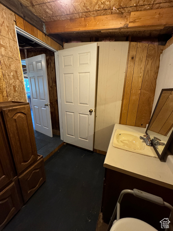 Interior space with beamed ceiling, vanity, and wooden walls