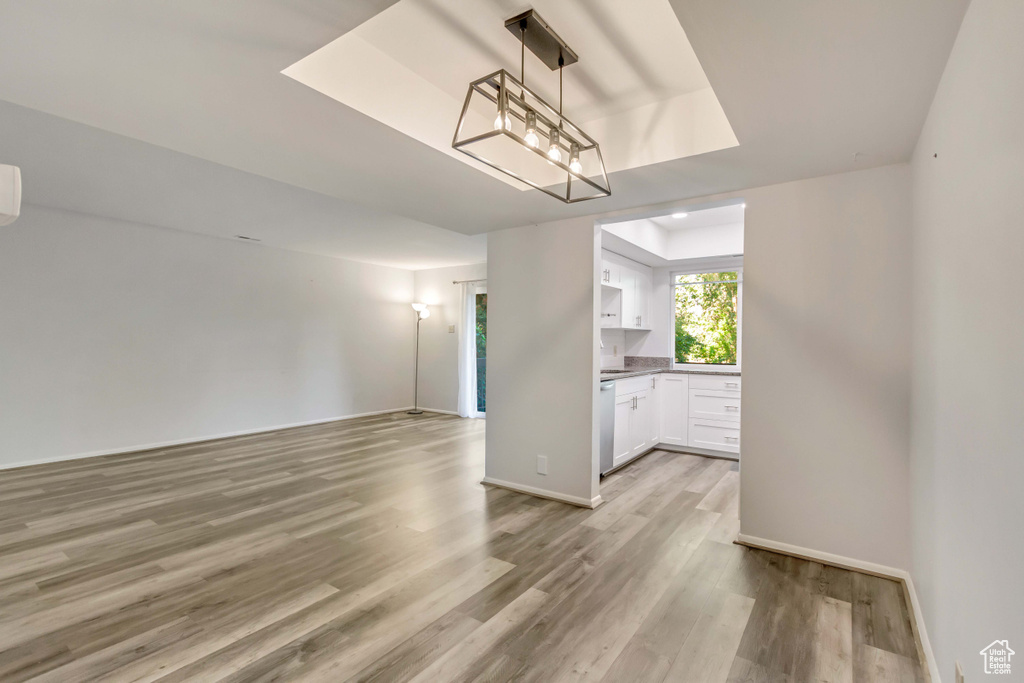 Unfurnished living room featuring an inviting chandelier and light hardwood / wood-style floors