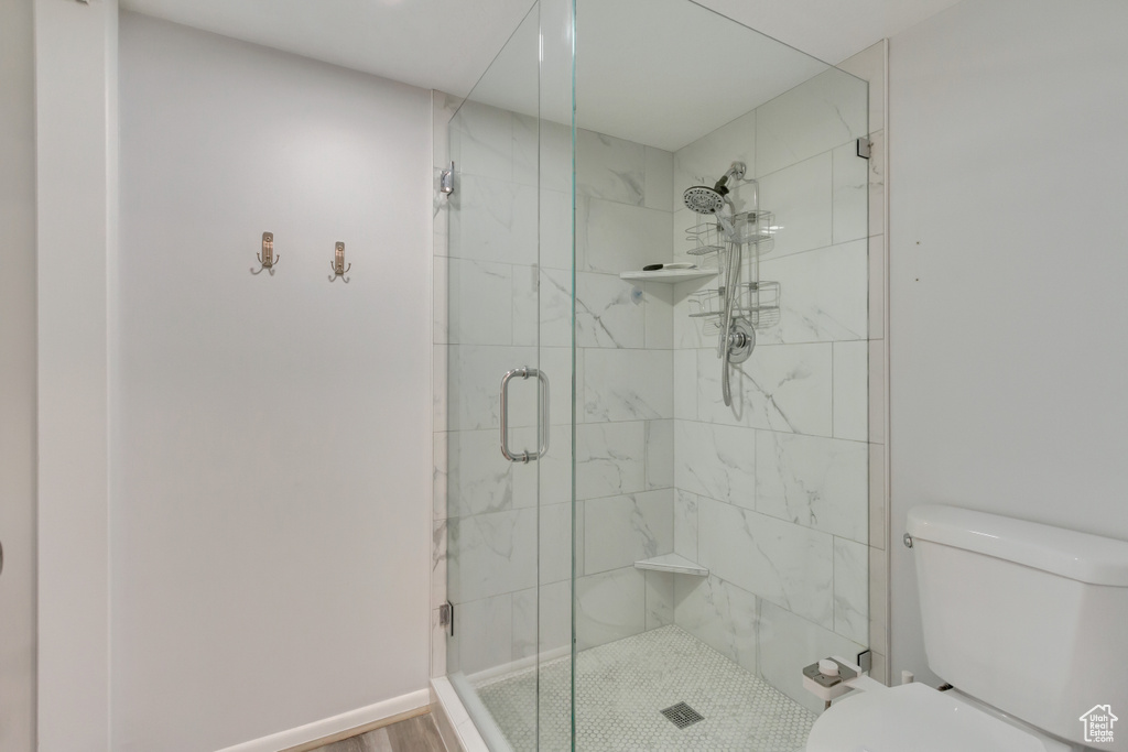 Bathroom featuring wood-type flooring, a shower with shower door, and toilet