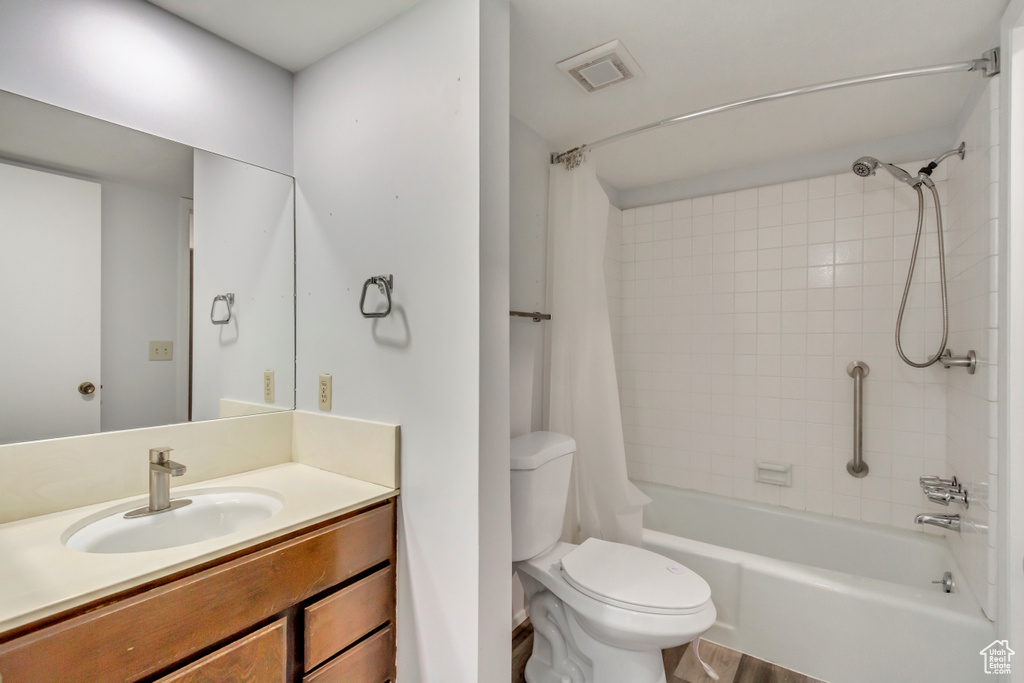 Full bathroom with shower / bathtub combination with curtain, toilet, vanity, and hardwood / wood-style flooring