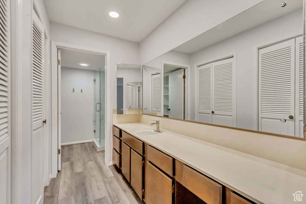 Bathroom featuring a shower with door, vanity, and hardwood / wood-style flooring