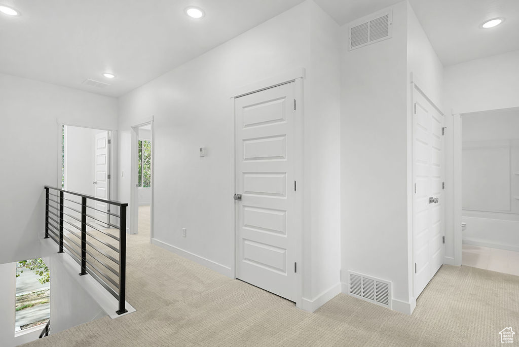 Hallway featuring light colored carpet