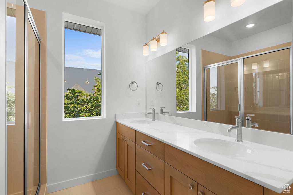 Bathroom featuring tile patterned flooring, vanity, and a shower with door