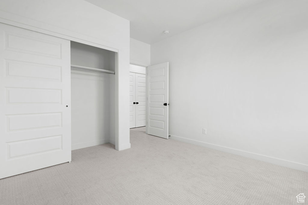 Unfurnished bedroom with light colored carpet and a closet