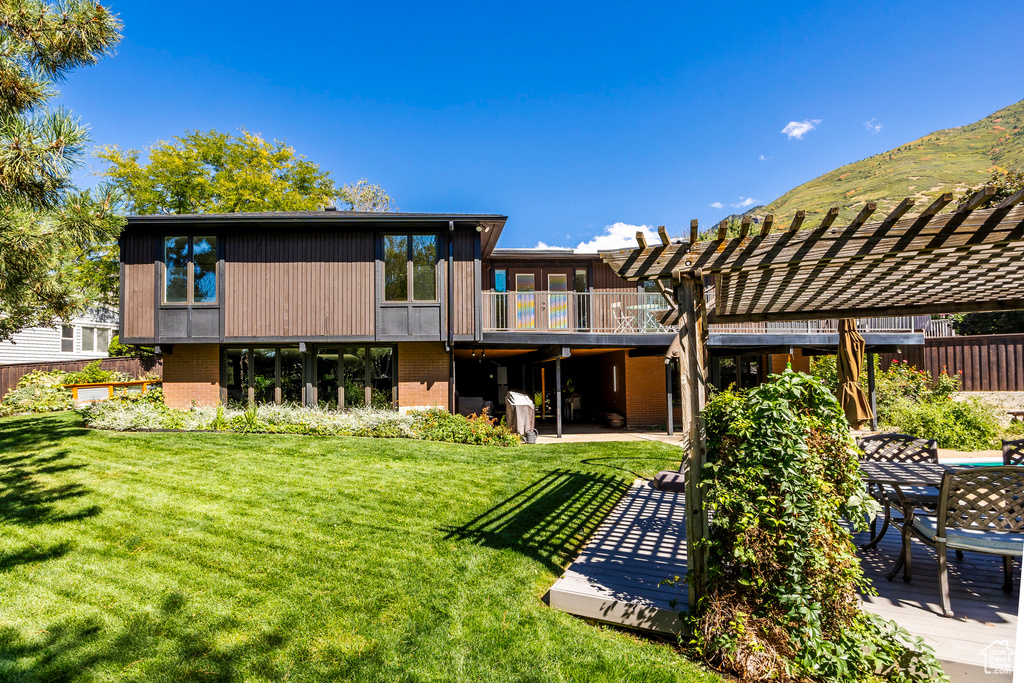 Rear view of house with a pergola, a patio area, and a lawn