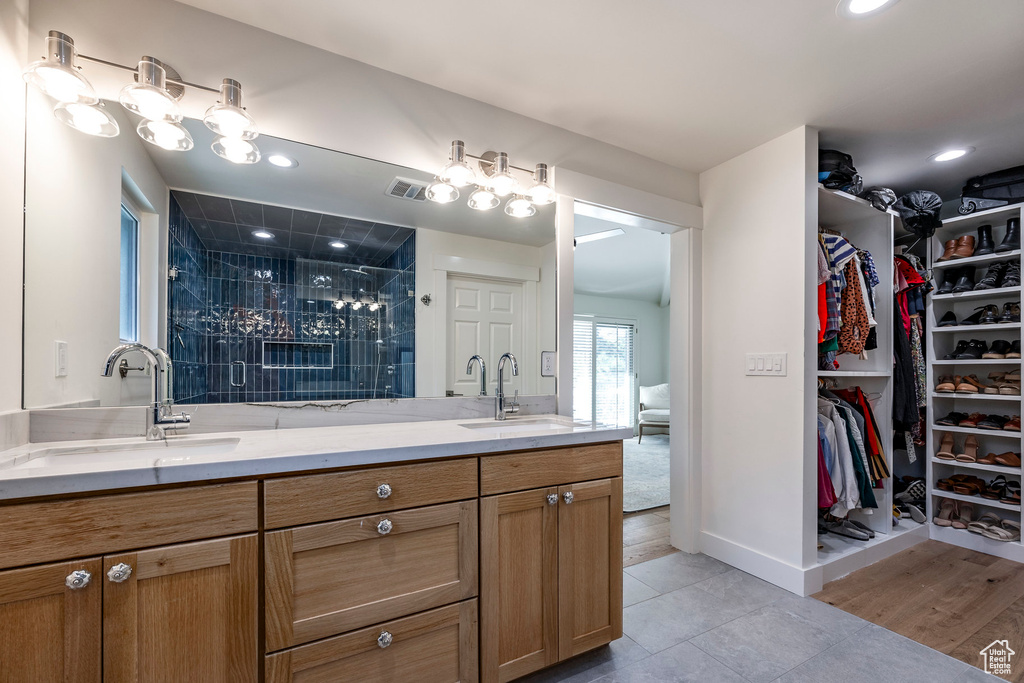 Bathroom with wood-type flooring, a tile shower, and vanity