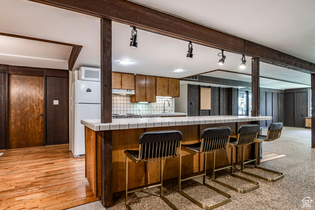 Kitchen featuring tile countertops, white appliances, light hardwood / wood-style floors, and track lighting