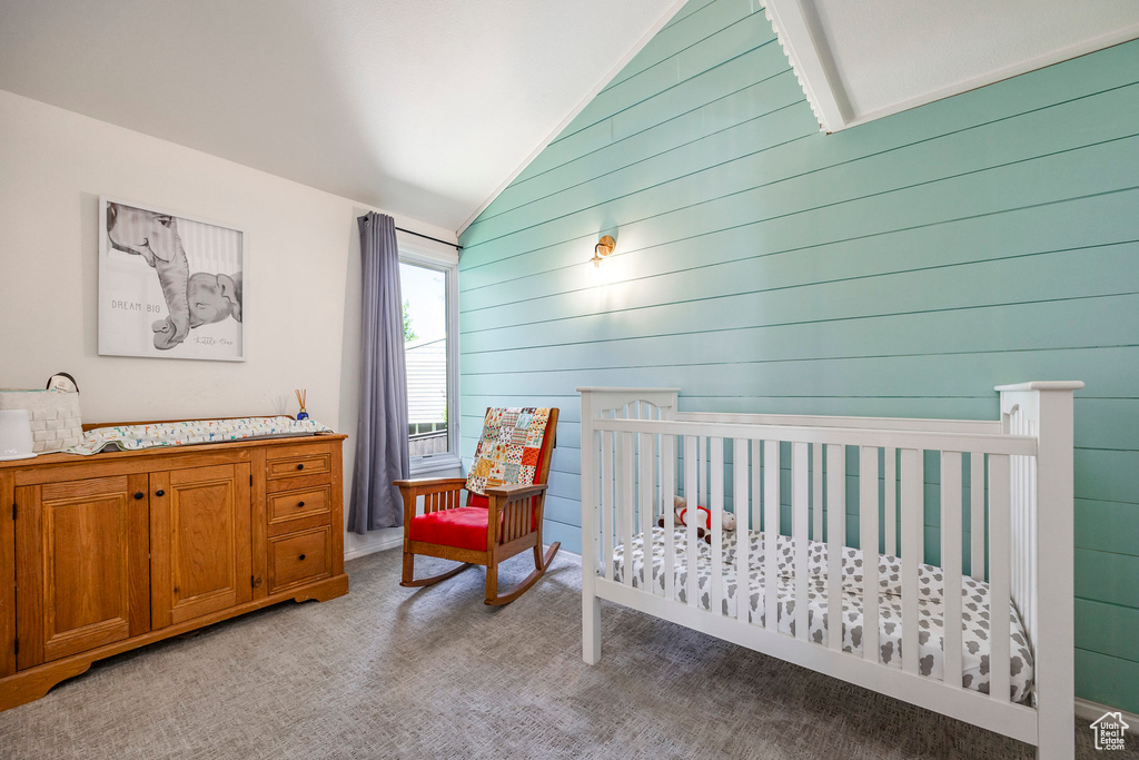 Carpeted bedroom featuring wood walls and vaulted ceiling