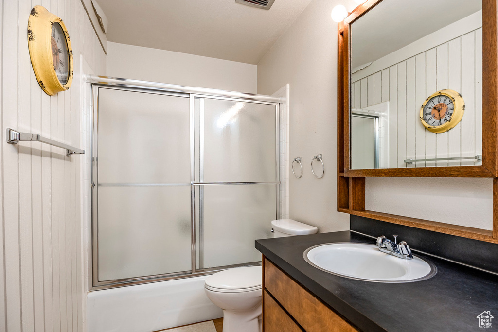 Full bathroom featuring enclosed tub / shower combo, vanity, and toilet