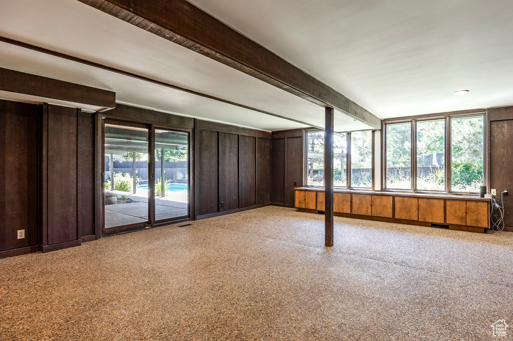 Unfurnished living room with wood walls and beamed ceiling