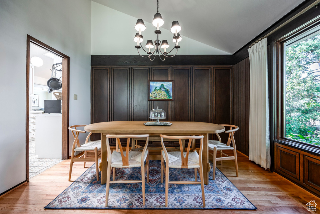 Dining area with an inviting chandelier, light hardwood / wood-style floors, and vaulted ceiling