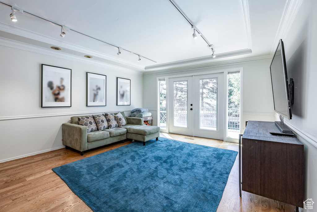 Living room featuring french doors, light wood-type flooring, crown molding, and rail lighting