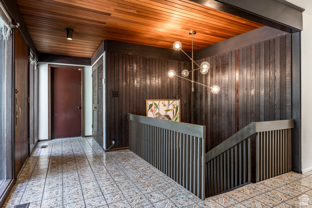 Corridor featuring wooden ceiling, wooden walls, and a notable chandelier