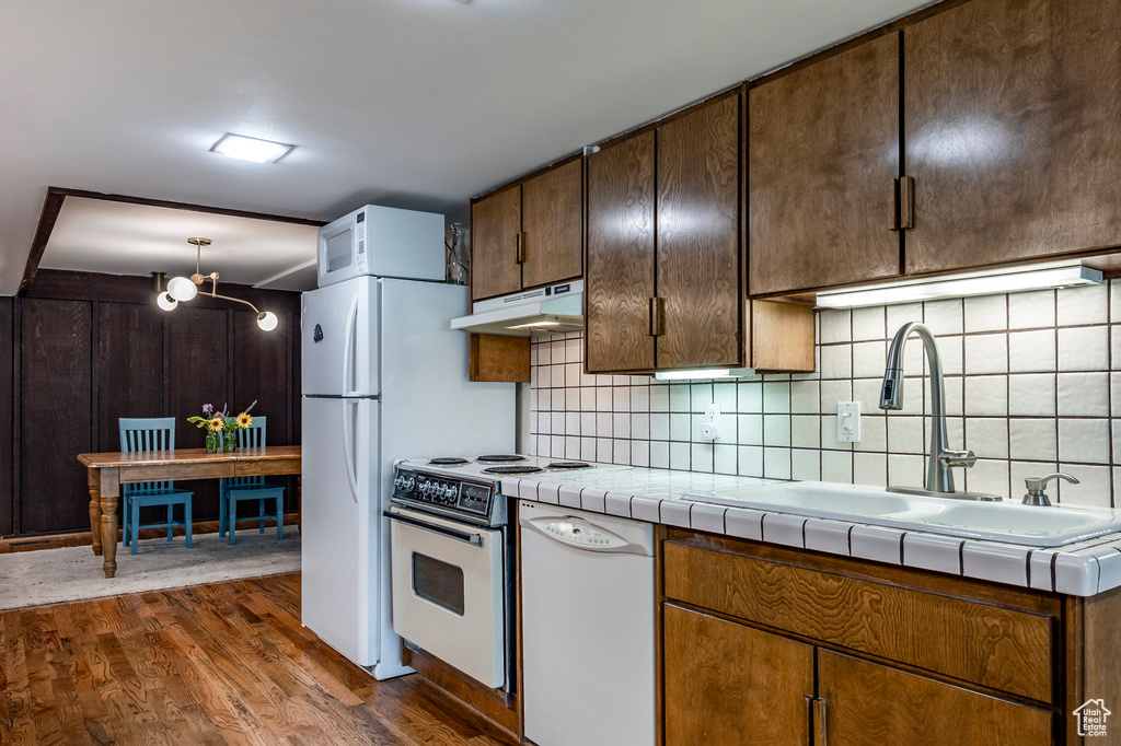 Kitchen with sink, decorative backsplash, white appliances, tile countertops, and dark hardwood / wood-style flooring