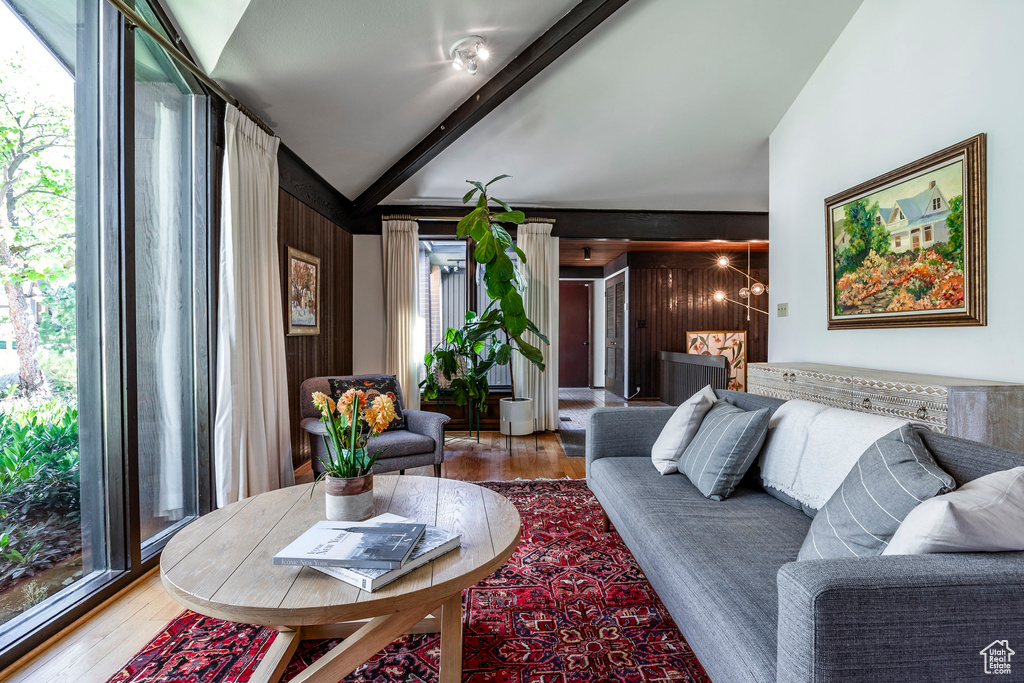 Living room featuring beam ceiling, wooden walls, and hardwood / wood-style floors