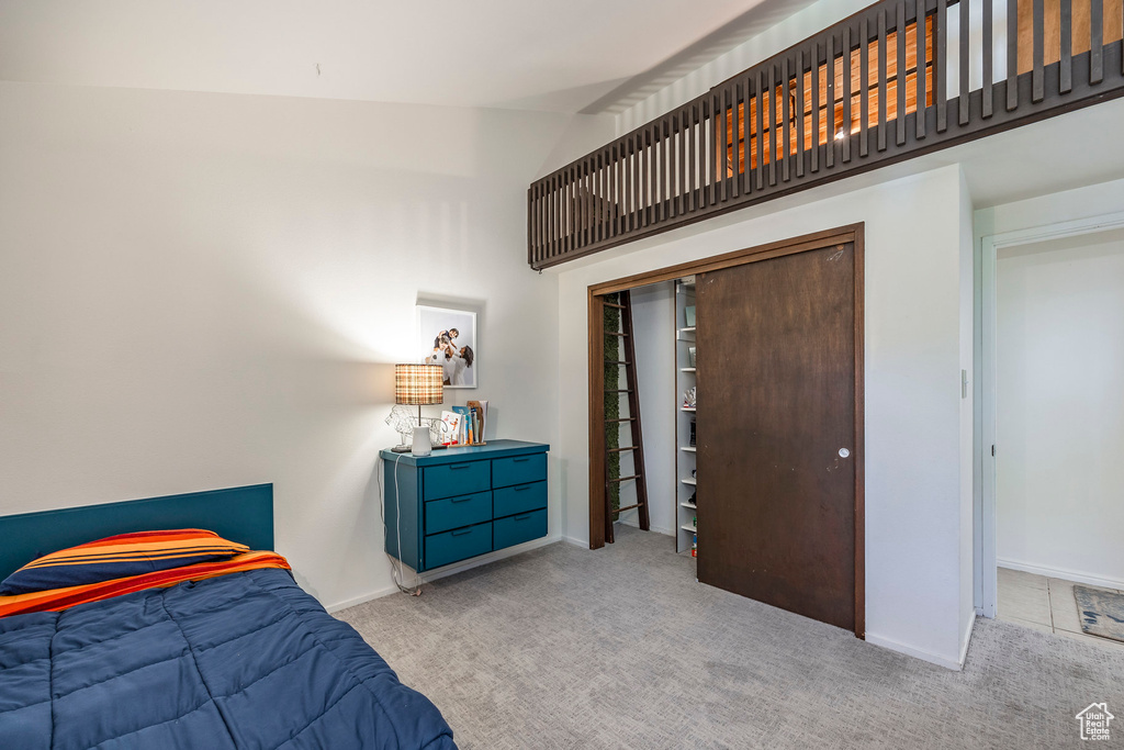 Carpeted bedroom featuring a closet and high vaulted ceiling