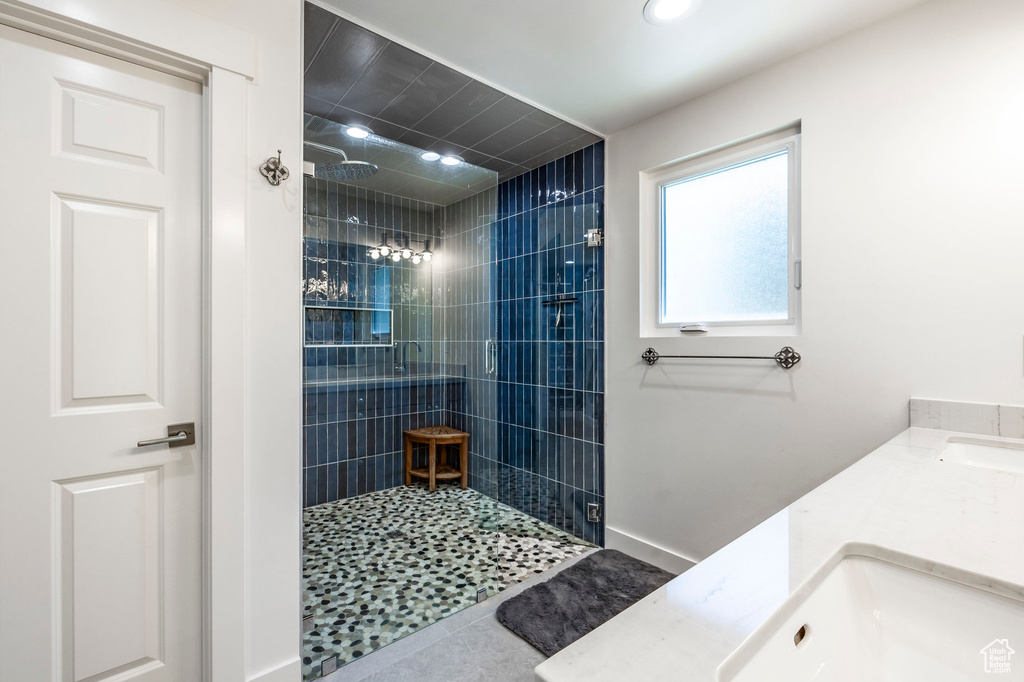 Bathroom with a tile shower, tile patterned flooring, and vanity