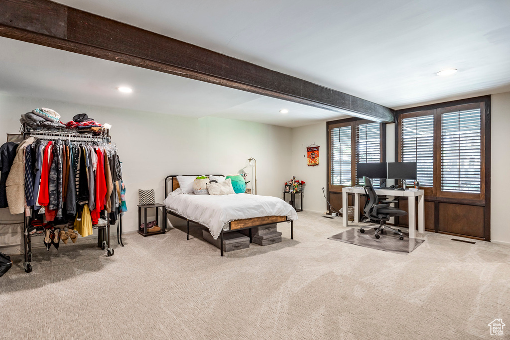 Bedroom with beam ceiling and light colored carpet