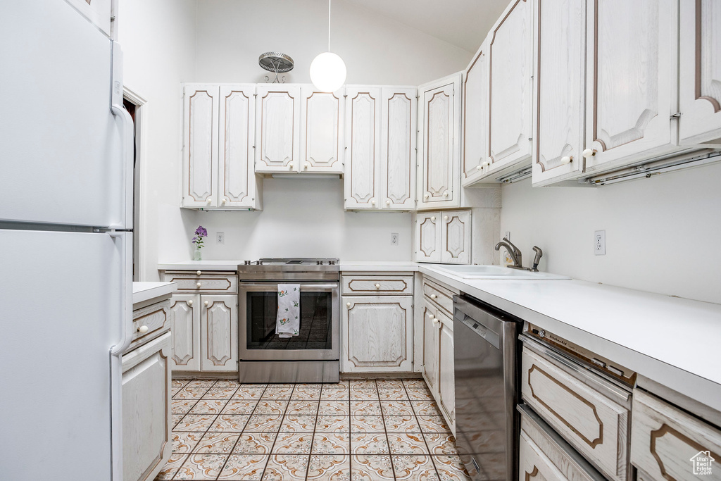 Kitchen featuring white cabinets, light tile patterned floors, sink, appliances with stainless steel finishes, and vaulted ceiling