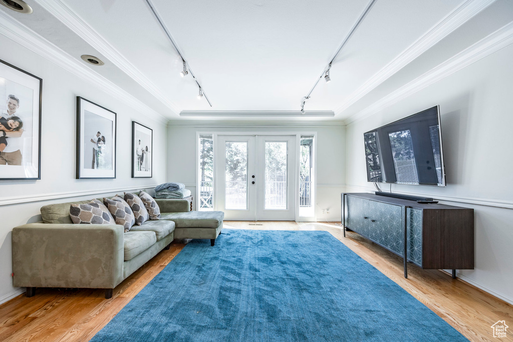 Living room with rail lighting, ornamental molding, light hardwood / wood-style flooring, and french doors