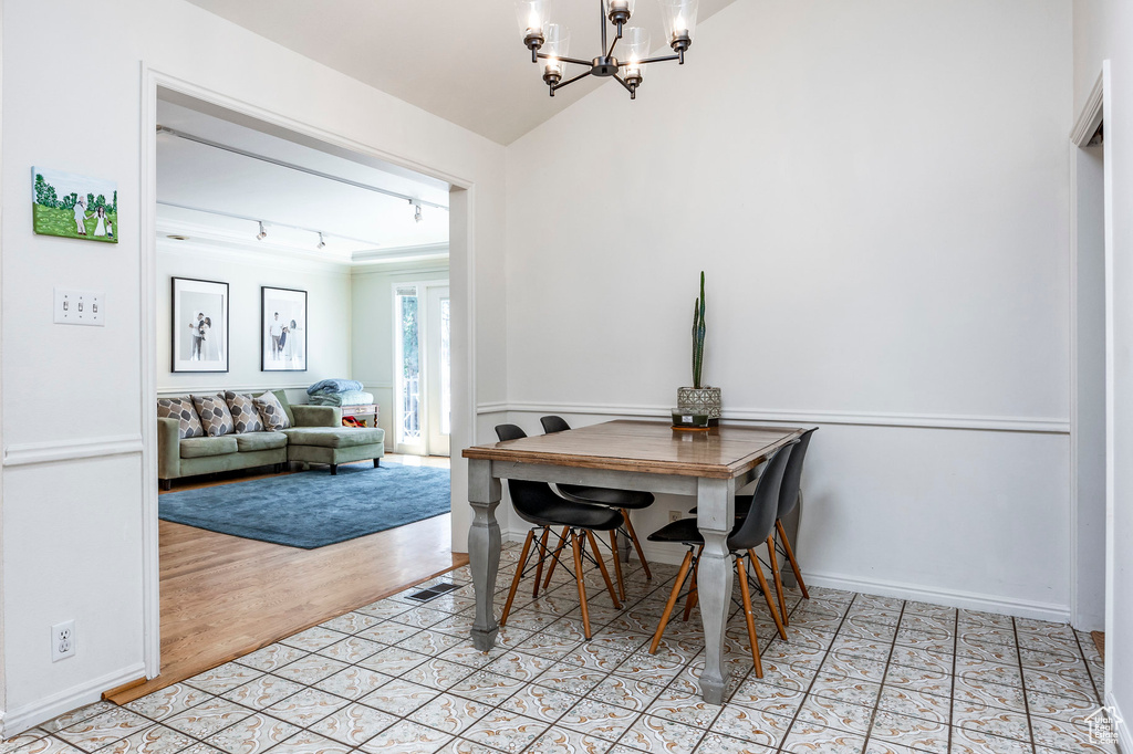 Dining space with a notable chandelier, lofted ceiling, and light hardwood / wood-style floors