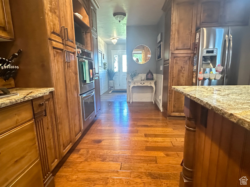 Kitchen with light stone counters, appliances with stainless steel finishes, and dark hardwood / wood-style floors