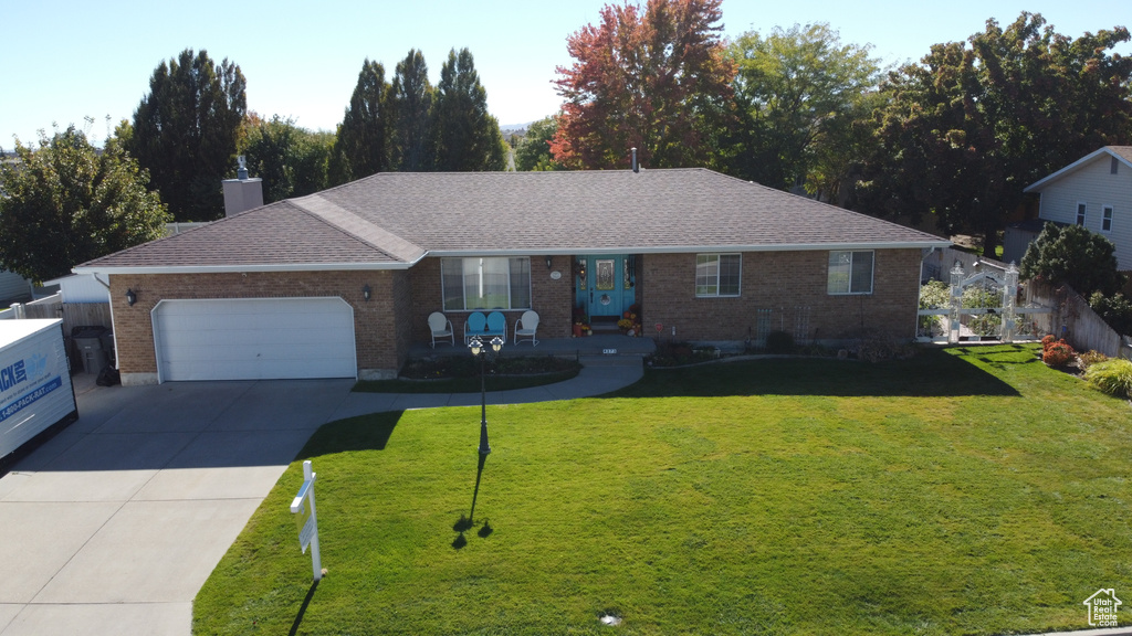 Ranch-style home featuring a front lawn and a garage