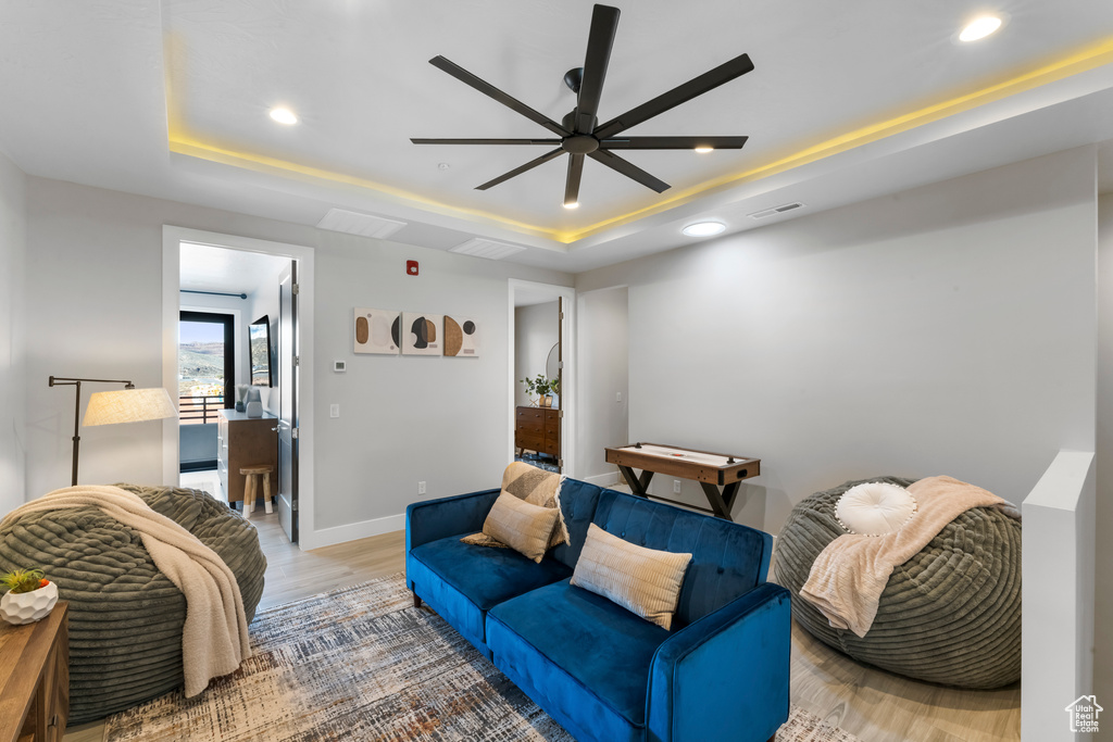 Living room with ceiling fan, hardwood / wood-style flooring, and a raised ceiling