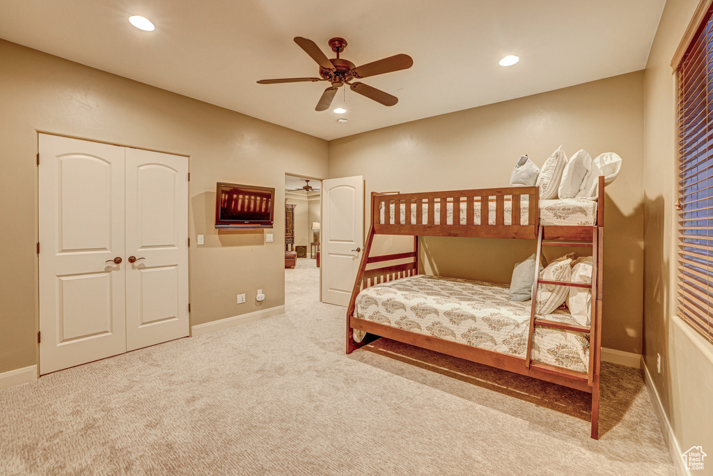 Carpeted bedroom featuring ceiling fan and a closet