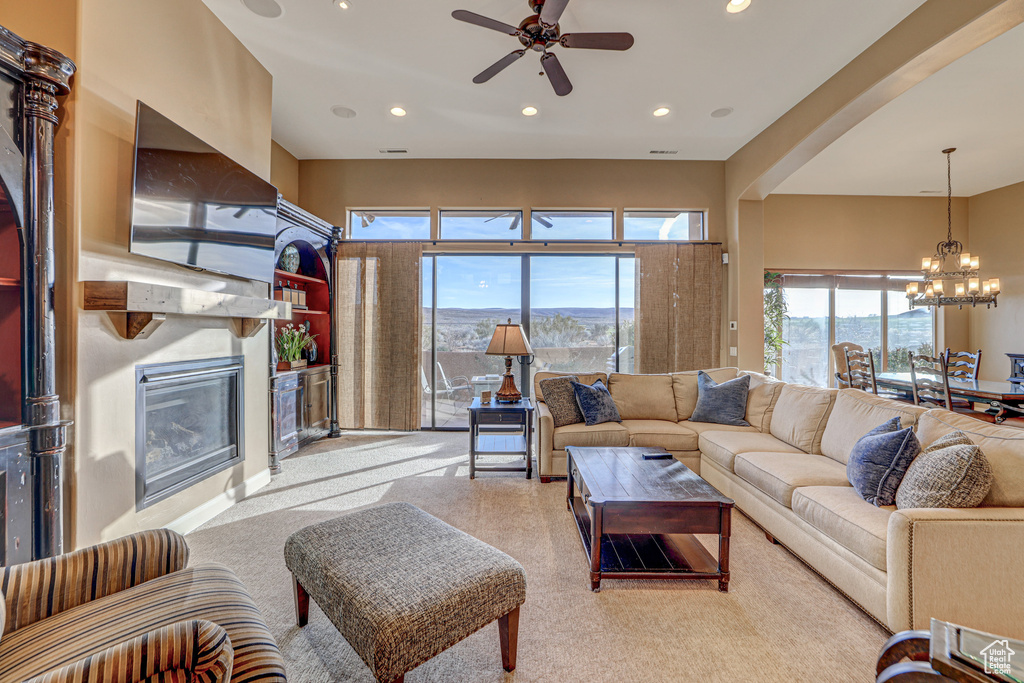 Living room featuring ceiling fan with notable chandelier and carpet flooring