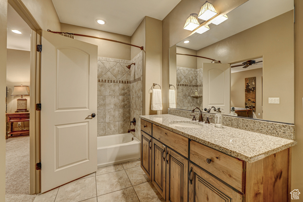 Bathroom featuring tile patterned floors, ceiling fan, tiled shower / bath combo, and vanity