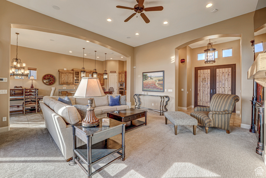 Carpeted living room featuring ceiling fan with notable chandelier and french doors