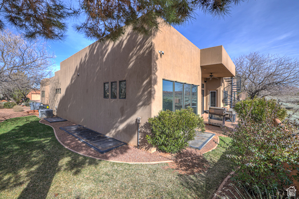 View of property exterior with a lawn, ceiling fan, and a patio area