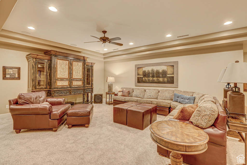 Living room featuring light carpet, a tray ceiling, and ceiling fan