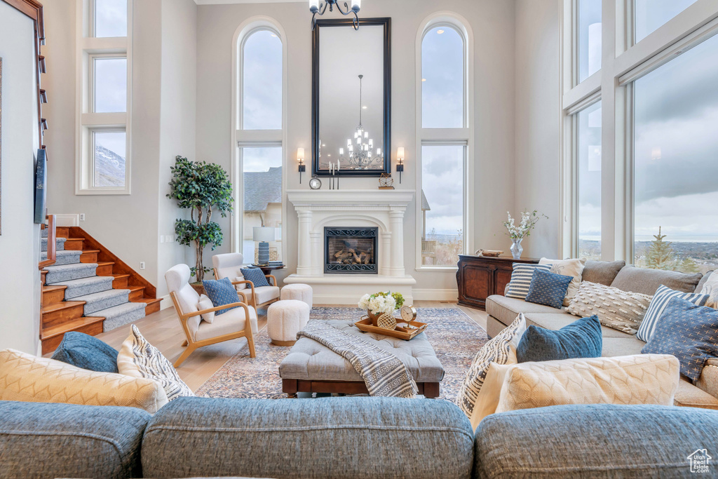 Living room featuring wood-type flooring, a notable chandelier, and a towering ceiling