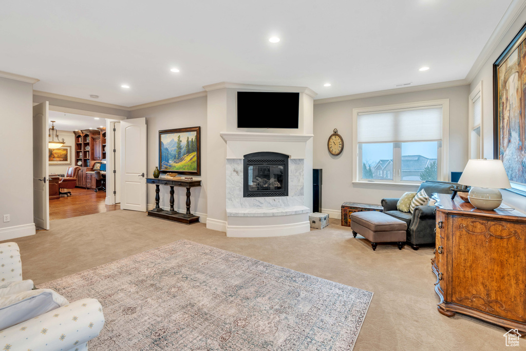 Living room with ornamental molding, light colored carpet, and a fireplace