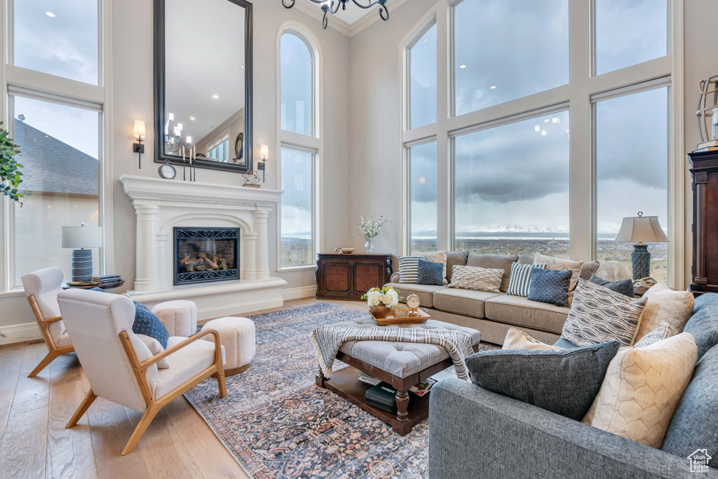 Living room with a high ceiling, ornamental molding, an inviting chandelier, and hardwood / wood-style flooring