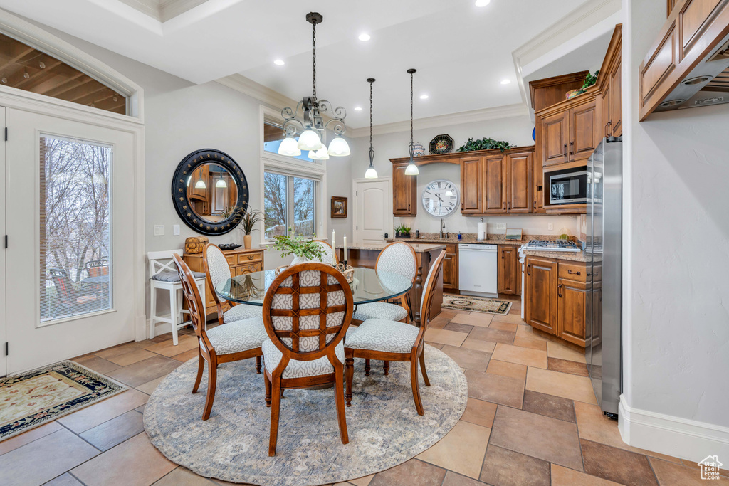 Dining area with an inviting chandelier, light tile patterned floors, a healthy amount of sunlight, and crown molding