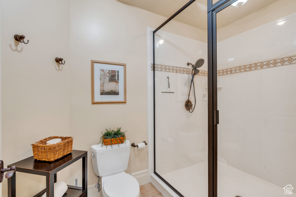 Bathroom with toilet, tile patterned floors, and a shower with shower door