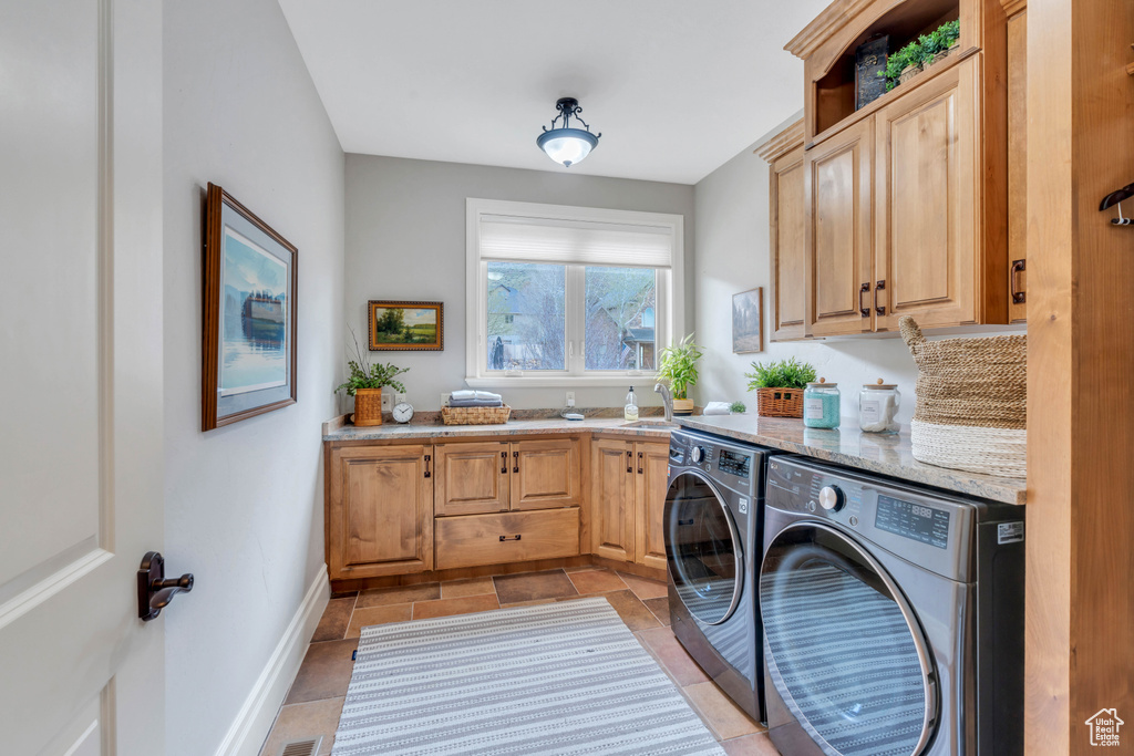 Laundry room featuring washing machine and clothes dryer, cabinets, light tile patterned floors, and sink