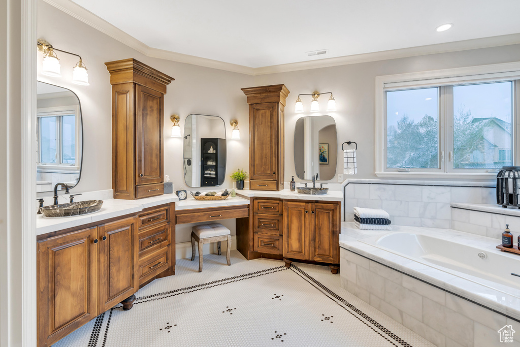 Bathroom with vanity, tile patterned floors, tiled bath, crown molding, and ornate columns