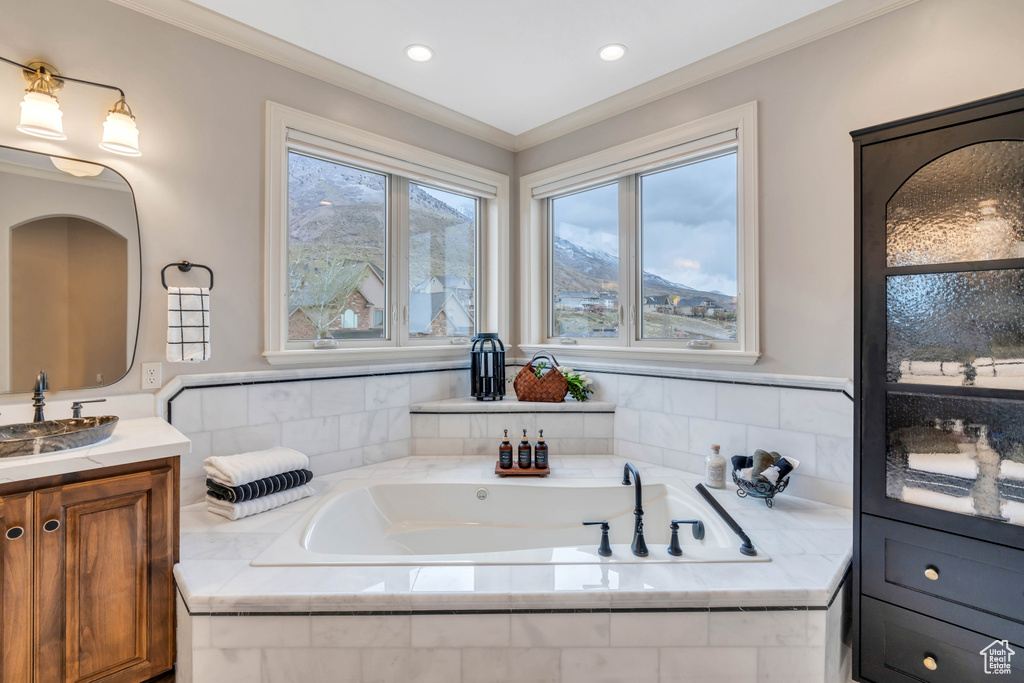 Bathroom featuring a relaxing tiled tub, vanity, and ornamental molding