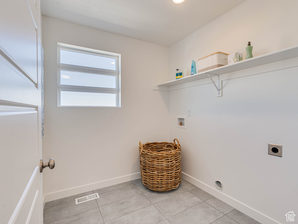 Washroom with hookup for an electric dryer, hookup for a washing machine, and light tile patterned floors