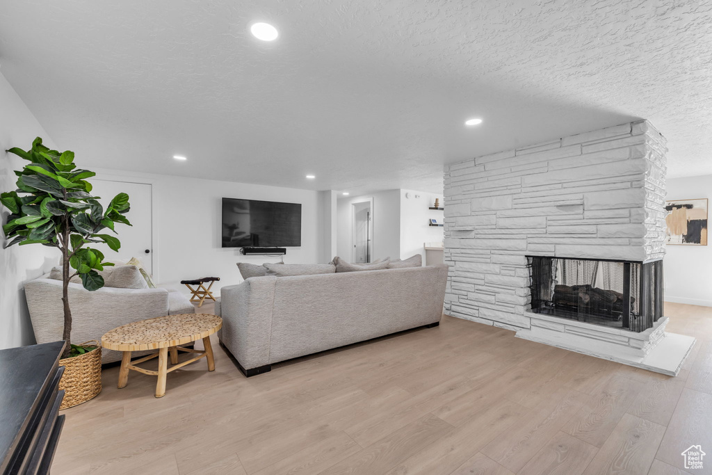 Living room featuring a textured ceiling, a fireplace, and light wood-type flooring