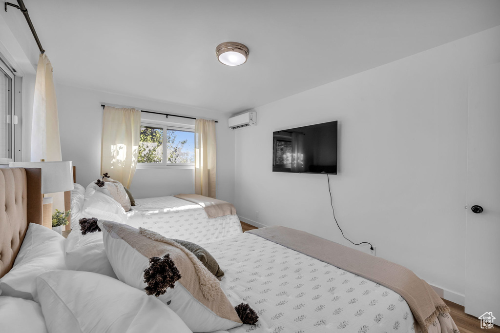 Bedroom featuring a wall mounted AC and hardwood / wood-style flooring