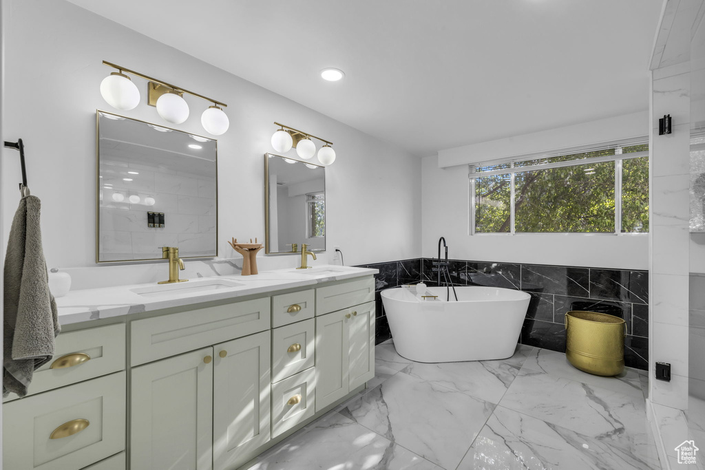 Bathroom featuring a tub to relax in, tile walls, and vanity