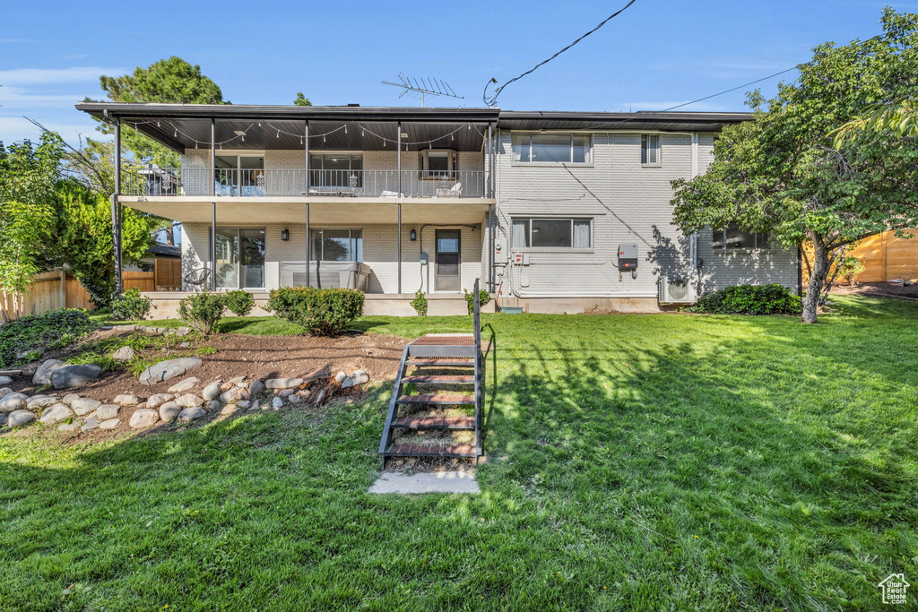 Back of property featuring a balcony and a yard