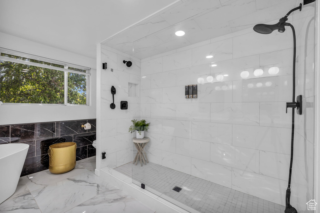 Bathroom featuring independent shower and bath and tile walls